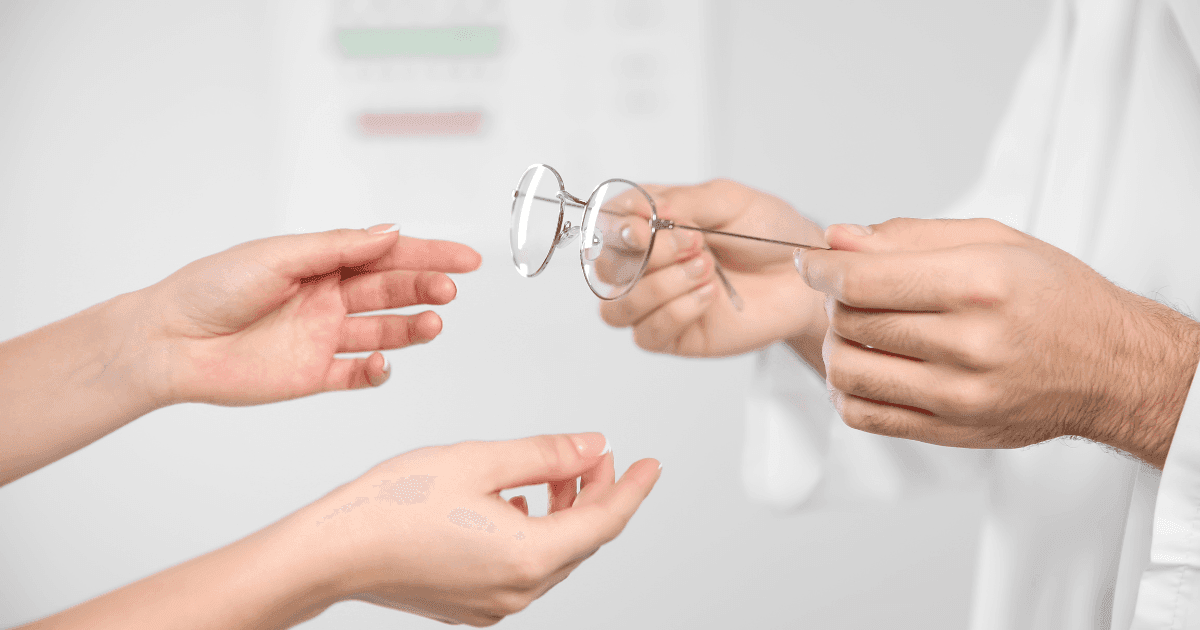 Eye care professional handing prescription glasses to a patient for hyperopia correction