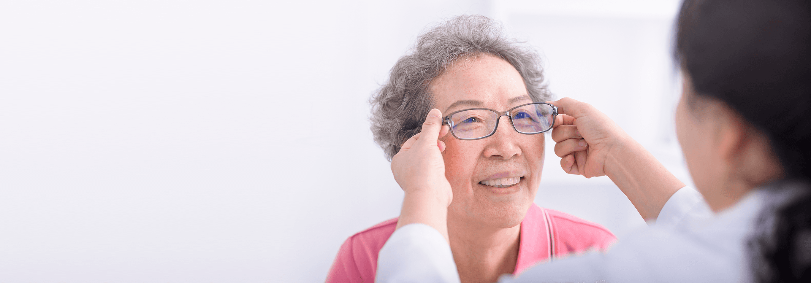 Optometrist fitting glasses for senior patient