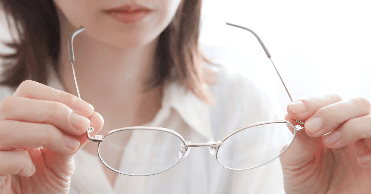 Woman holding eyeglasses, representing glasses as a common option for myopia correction