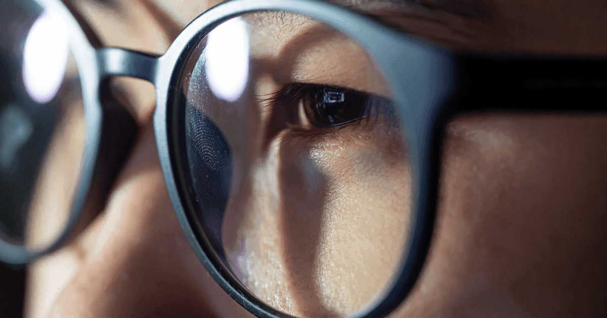 Close-up of an eye behind glasses, representing blurred or distorted vision caused by astigmatism