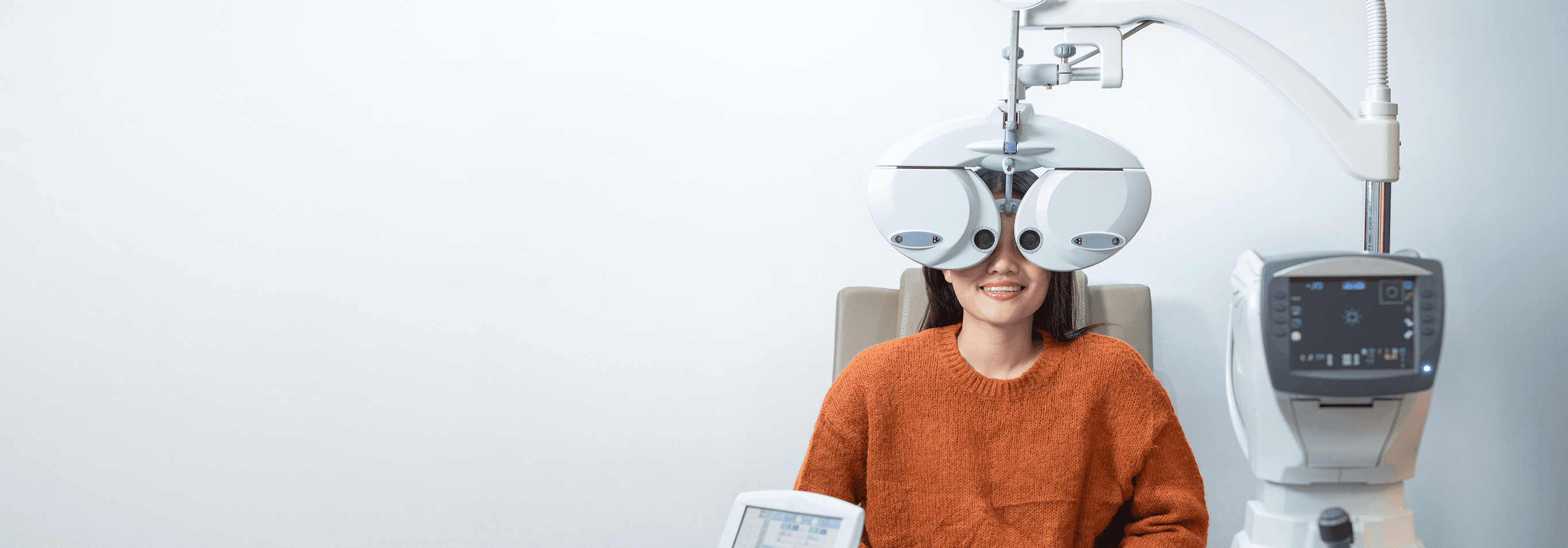 Patient using eye exam machine at optometry clinic.