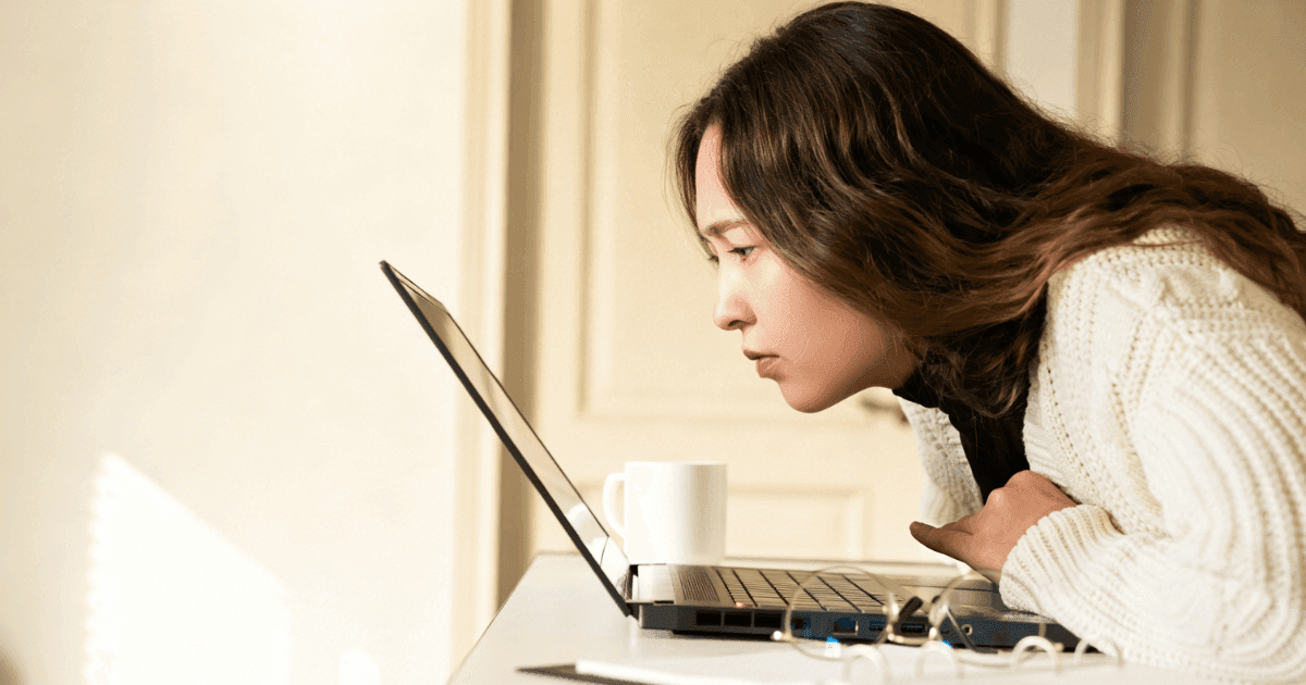 Asian woman using a laptop at close distance, illustrating near work and screen use as factors associated with myopia