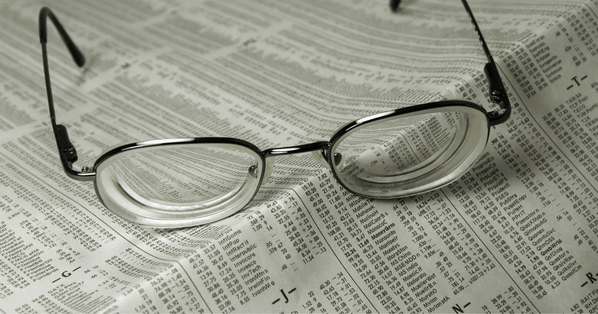 Eyeglasses placed on printed text, illustrating blurred near vision and difficulty focusing