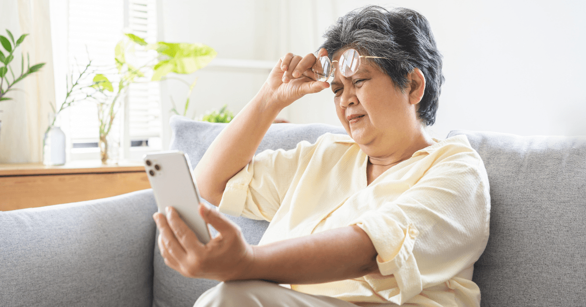 Older woman struggling to read text on a smartphone due to presbyopia (age-related long-sightedness