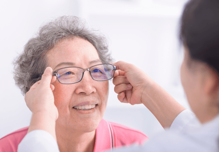 Optometrist fitting glasses for senior patient